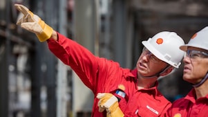 a person wearing a hard hat and gloves pointing at something