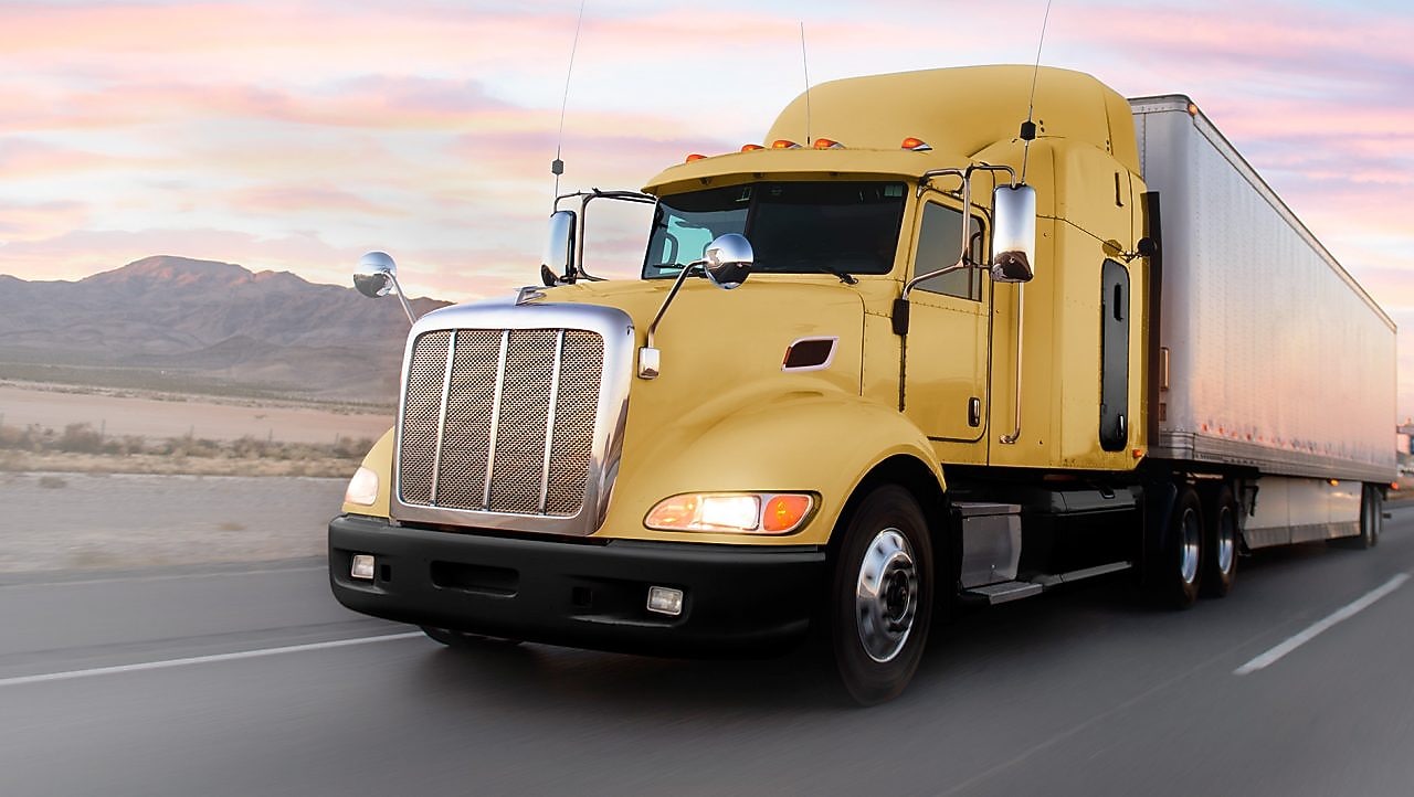 a yellow truck driving down a road at dusk