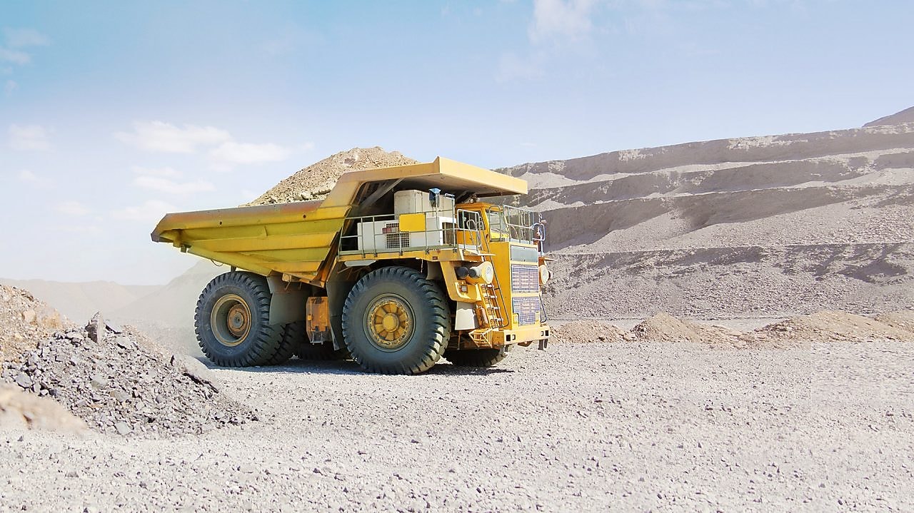 yellow dumper truck driving through gravel