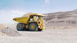 yellow dumper truck driving through gravel