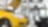 two cars in a garage, one yellow and one white, with their bonnets open, and some car tyres in the background