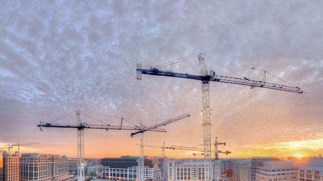 three cranes on a building site at dusk
