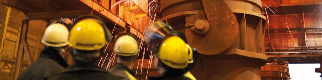 workers watching heavy machinery in a metal processing plant