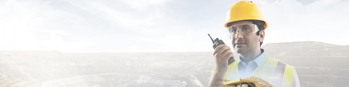 worker in yellow hard hat transposed onto a background of cliffs and a large yellow truck