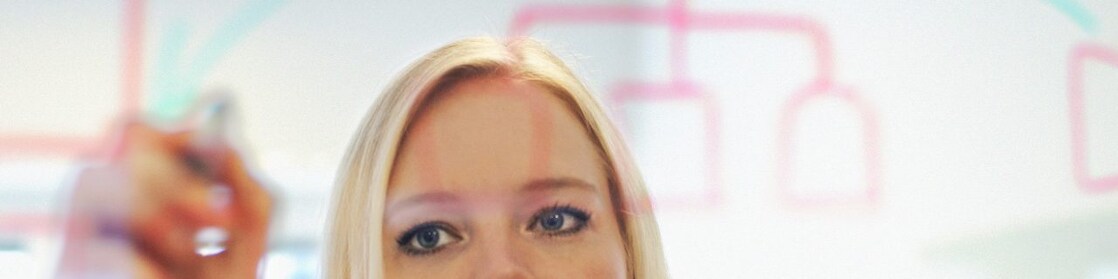 Sweden, Businesswoman writing on glass wall in office
