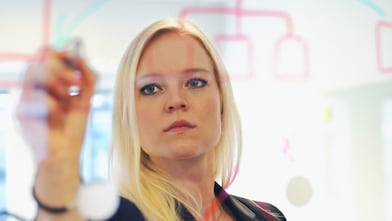 Businesswoman writing on glass wall in office