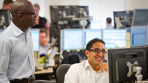 Two traders at Shell working together and smiling.