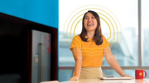 A female Shell employee in the office happily gazing afar