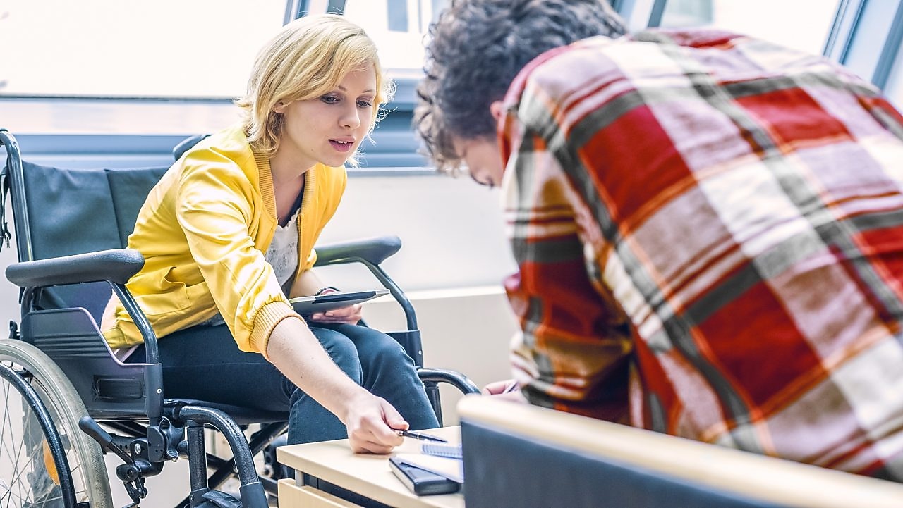 Woman in a wheelchair talking to a man