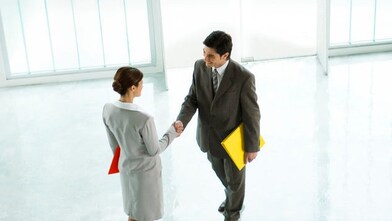 Businessman and businesswoman shaking hands in lobby
