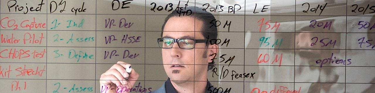 employee writing on transparent board.