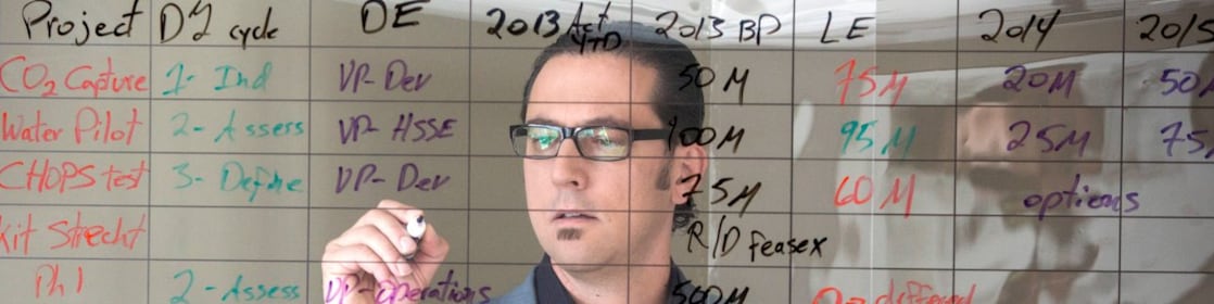 employee writing on transparent board.