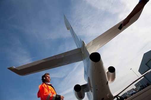 bottom up view of staff walking behind the tail end of a plane