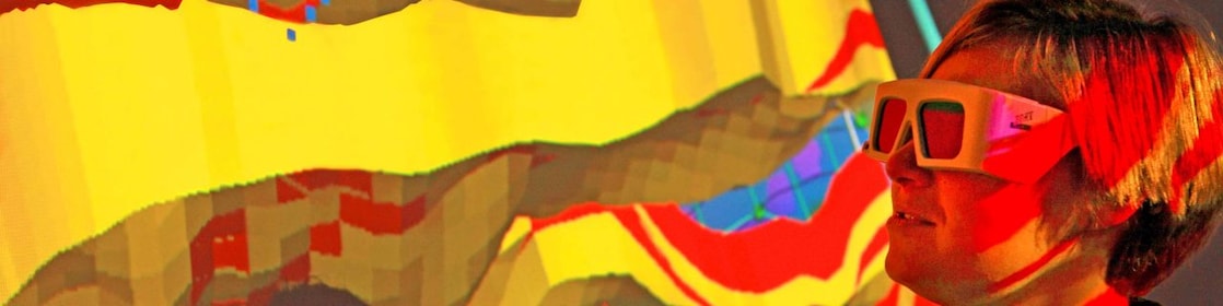A woman with special goggles examines a 3D wall projection of a geological map 