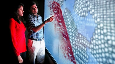Shell mentor Krishna with his mentee Mounika, pointing to a wall panel