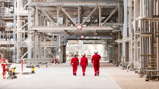 Three engineers walking through refinery grounds
