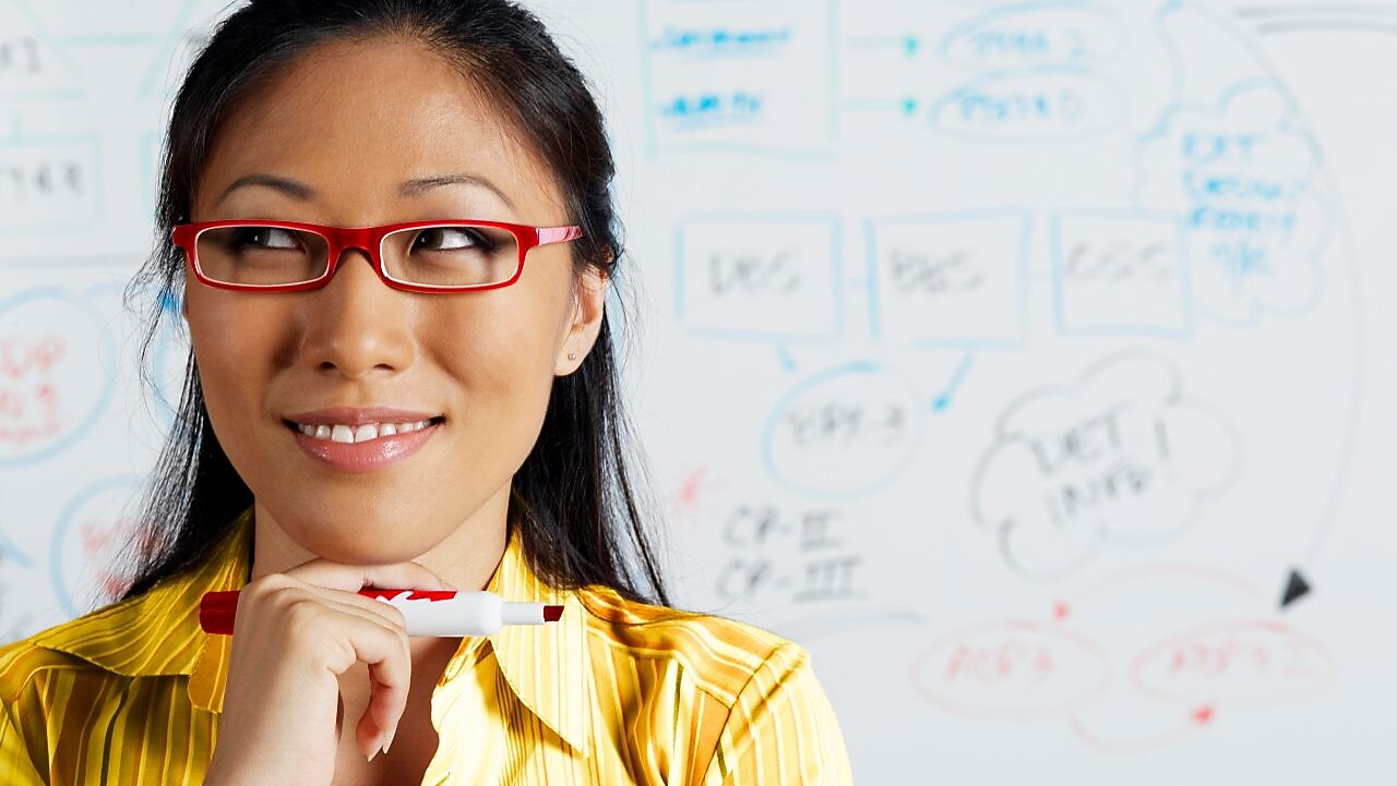 Close up of Asian businesswoman smiling in front of whiteboard