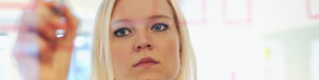 Sweden, Businesswoman writing on glass wall in office