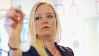 Businesswoman writing on glass wall in office