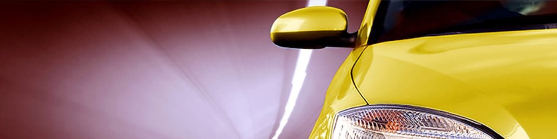 Front of a yellow car driving through a tunnel, right front light and wing mirror in view