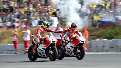 Two bikers shaking hands as they ride