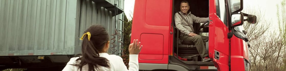 Man in red truck cab with door open waving to his daughter