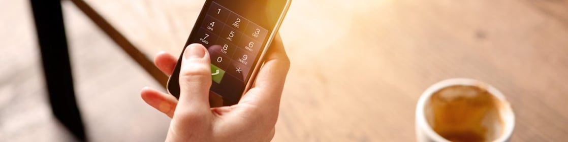 Man holding a mobile phone and drinking coffee