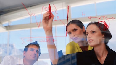 Businesswoman drawing graphs on glass